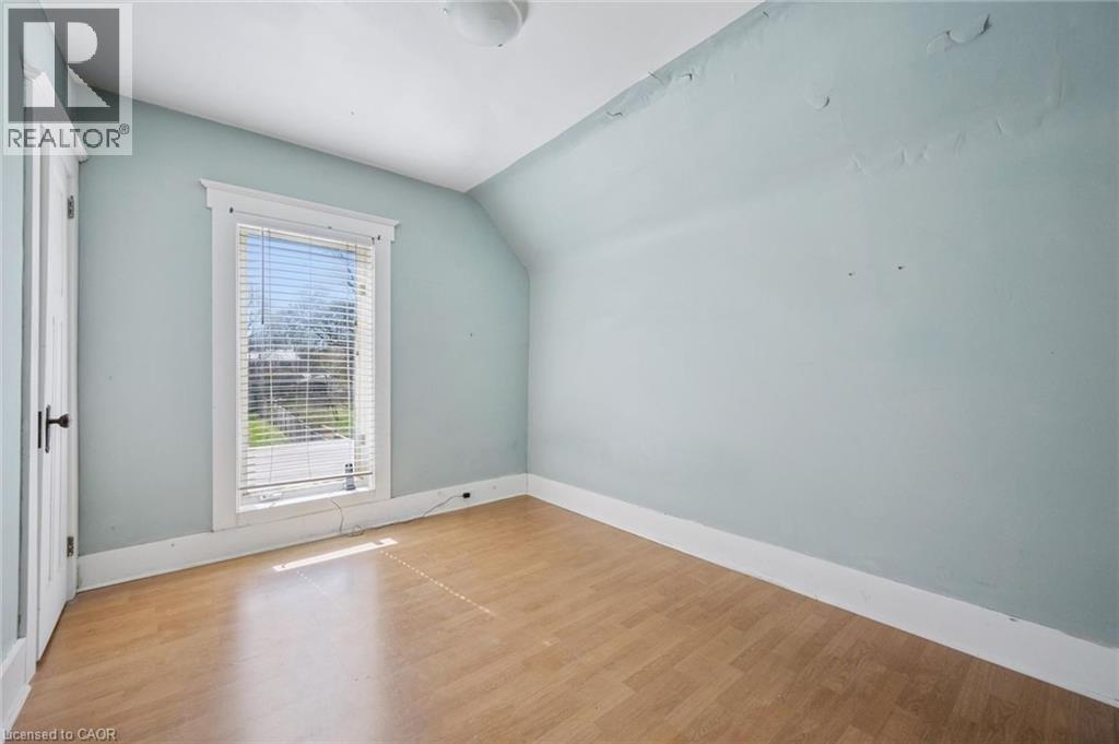 Bright room featuring wood-finish flooring, a single window with blinds, and a white paneled door with dark hardware