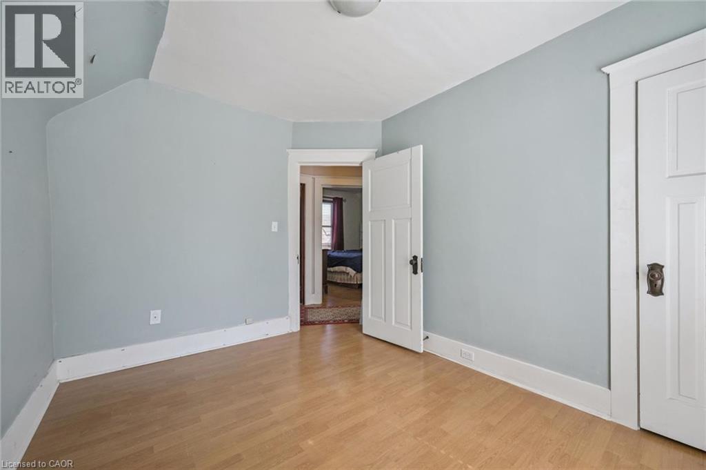 Room featuring wood-finish flooring, light blue wall paint, white baseboards, and white paneled doors with dark hardware