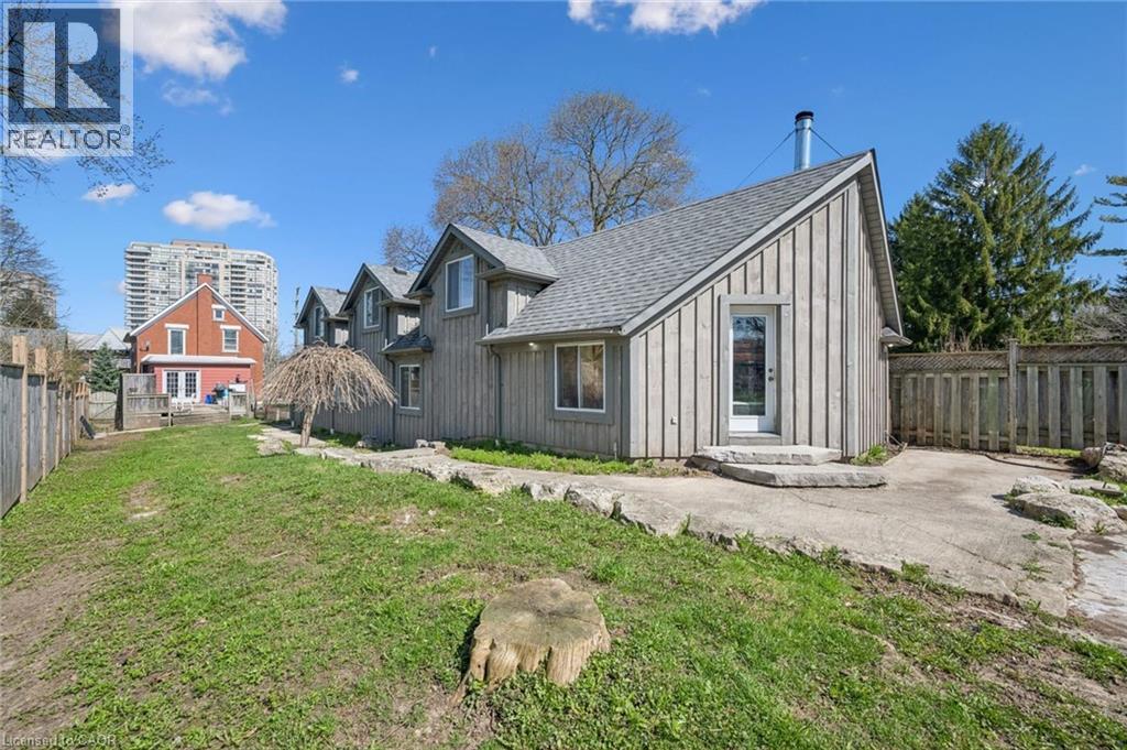 Rear exterior of the property featuring vertical wood siding, multiple dormer windows, and an asphalt shingle roof
