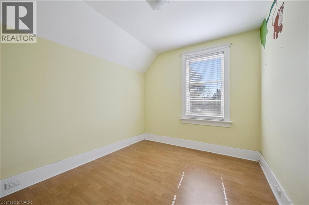 Room featuring wood-finish flooring, a single window with blinds, and light-colored walls
