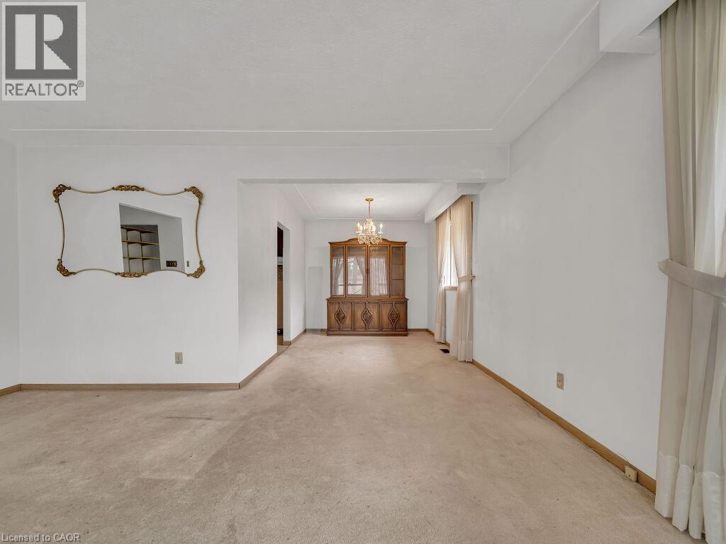 Open-concept living space featuring neutral-toned carpeting, white painted walls, and an ornate gold-framed mirror