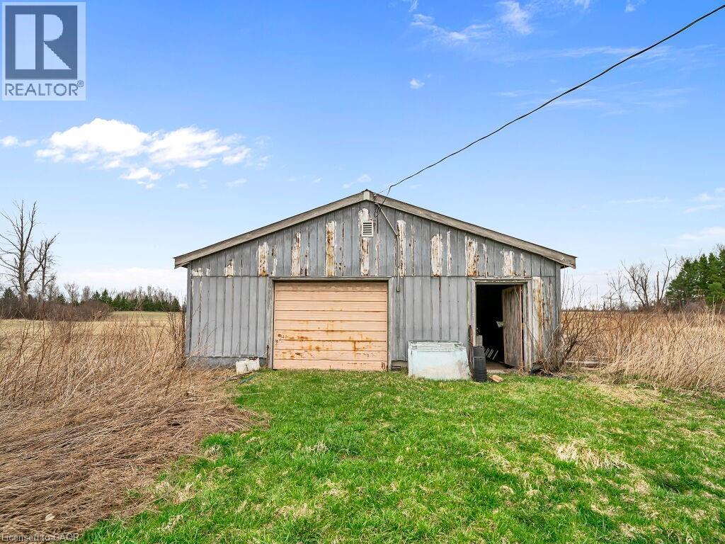 Outbuilding with a peaked roof, wood siding, a roll-up garage door, and a separate side entrance