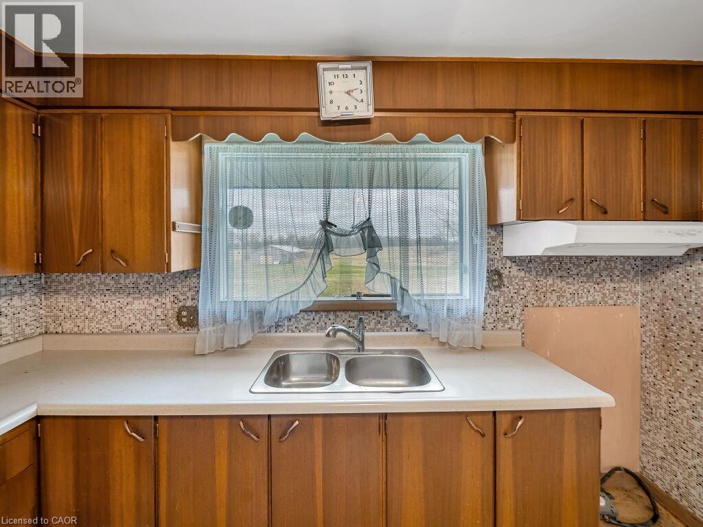 Kitchen featuring a double basin stainless steel sink, laminate countertops, wood-finish cabinetry, and a mosaic tile backsplash