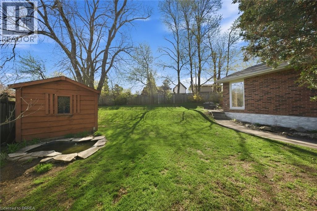 Expansive sloped lawn area with a wood-sided storage shed and a stone-edged pond