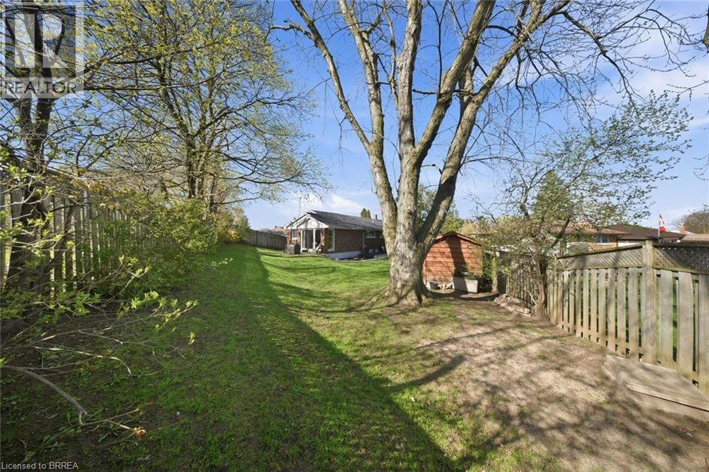 Expansive backyard featuring a manicured lawn, established trees, and perimeter fencing