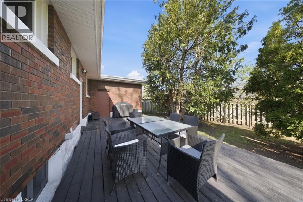 Expansive wood-finish deck bordered by a brick exterior and a privacy fence