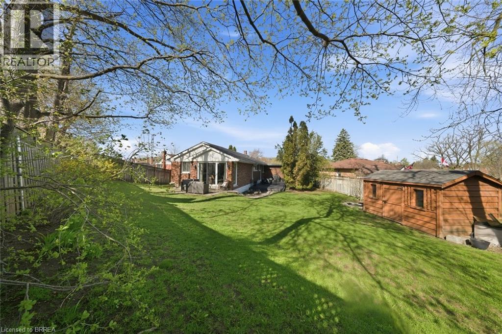 Expansive sloped backyard featuring a manicured lawn, mature trees, and a detached wooden shed