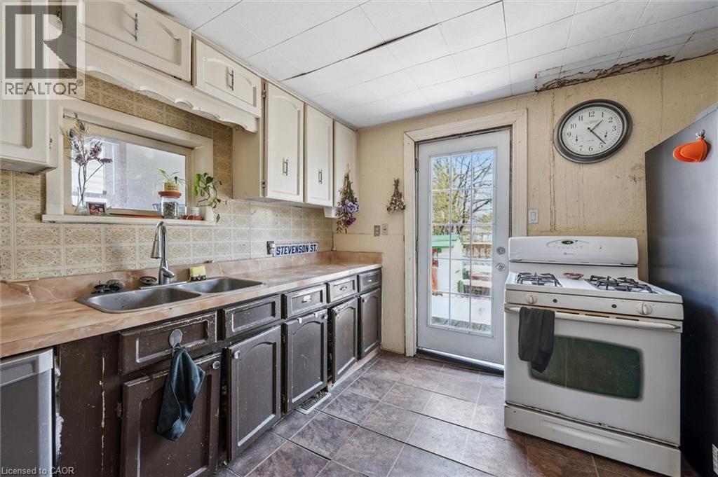 Kitchen featuring a double basin sink with a single-handle faucet, a built-in dishwasher, an oven with a stovetop, and overhead and under-counter cabinetry