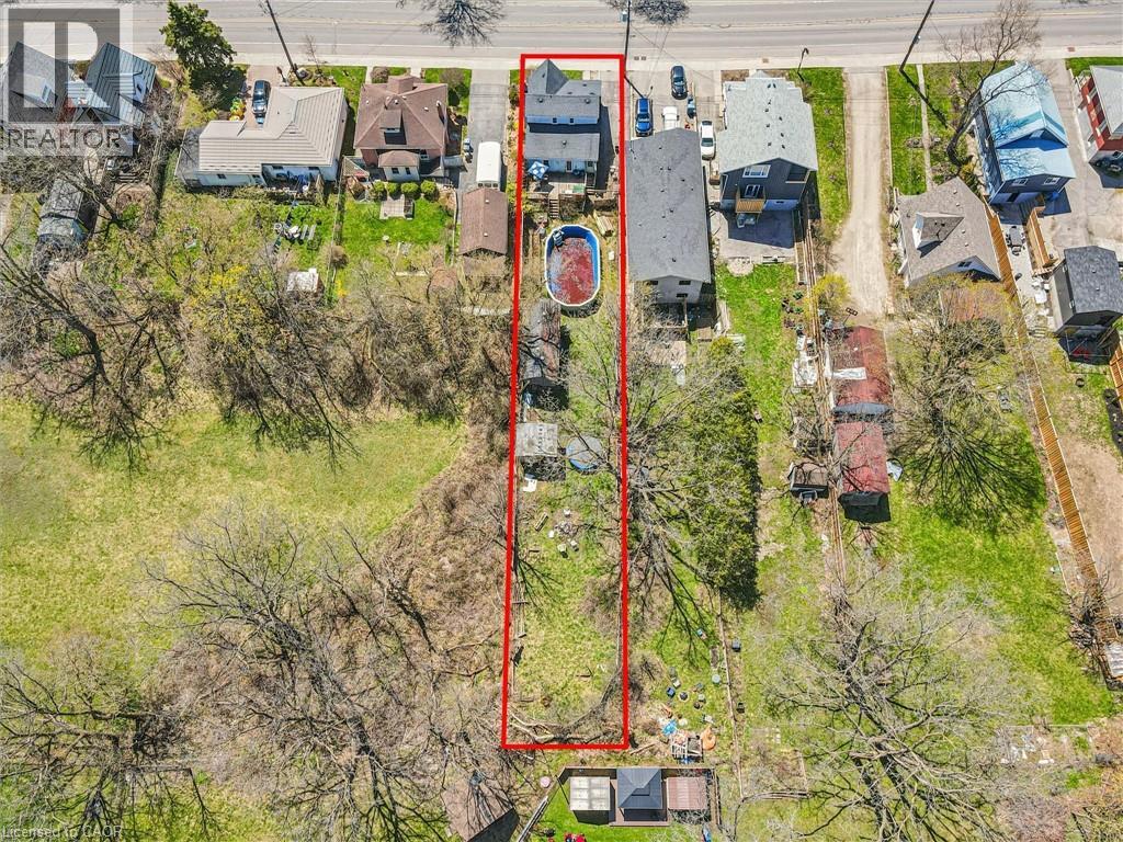 Aerial perspective highlighting the property with a two-story residence, a detached garage, and a fenced yard with an above-ground pool
