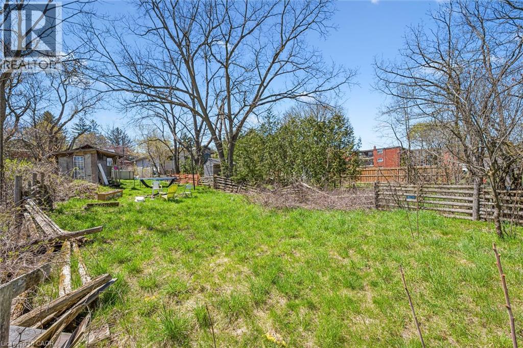 Expansive backyard featuring a large grassy area, established trees, and a wooden fence