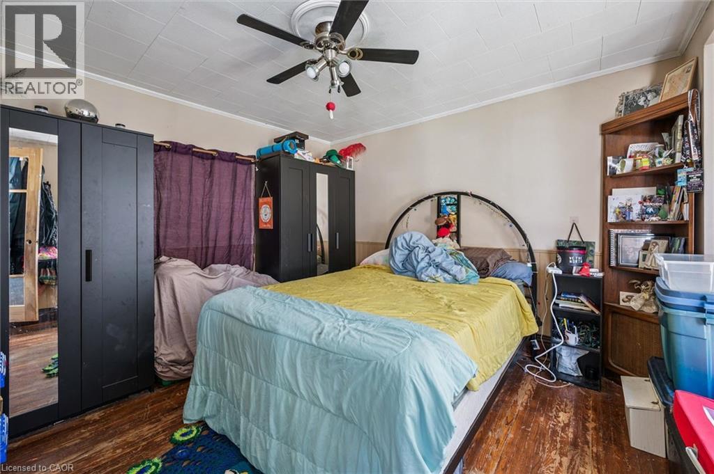 Room featuring wood-finish flooring, a ceiling fan with light fixture, and a built-in corner shelving unit