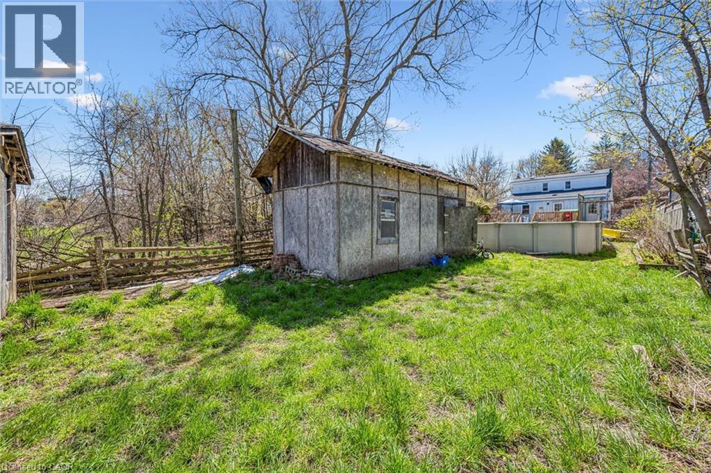 Grassed yard with a wood-sided outbuilding, a partial wood fence, and an above-ground pool