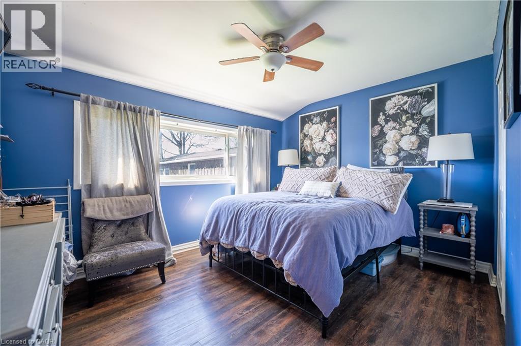 Spacious room featuring wood-finish flooring, a ceiling fan with light fixture, and a large window with white trim