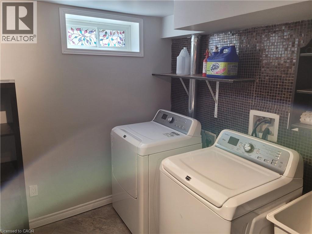 Dedicated laundry area featuring a mosaic tile backsplash, built-in shelving, and a decorative stained-glass window