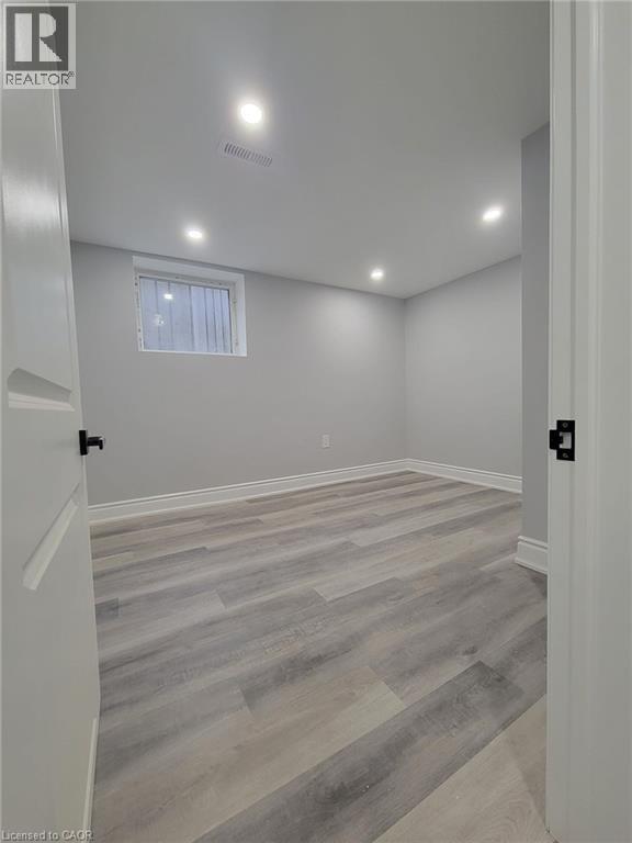 Room featuring light gray walls, wood-finish flooring, recessed lighting, and a white trim package