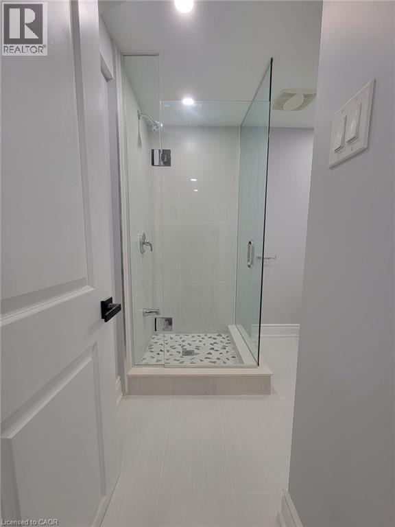 Modern glass-enclosed shower featuring a tiled base with decorative stone accents