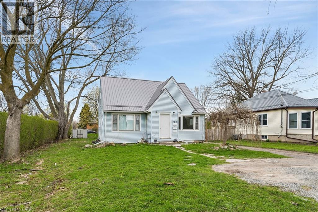 Gabled residence featuring light-colored siding, a metal roof, and a gravel driveway