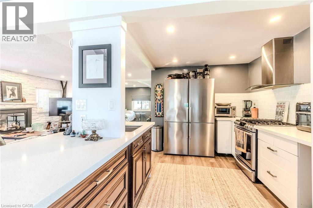 Open-concept kitchen featuring wood-finish flooring, stainless steel appliances, a white subway tile backsplash, white countertops, and recessed lighting