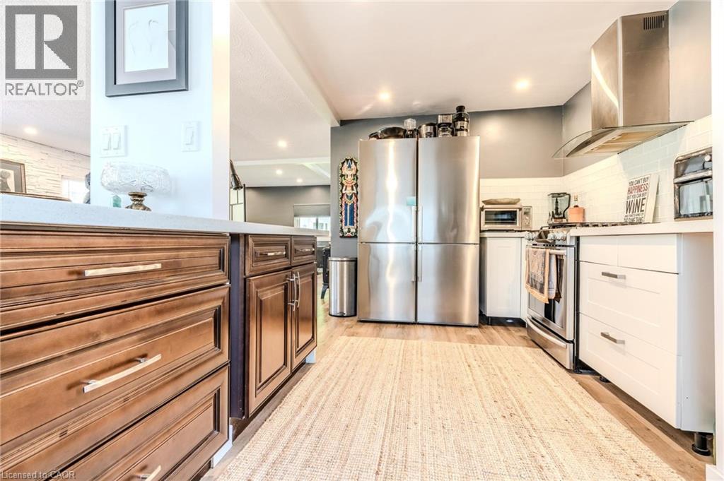 Contemporary kitchen featuring wood-finish flooring, two-tone cabinetry, stainless steel appliances, a tile backsplash, and recessed lighting