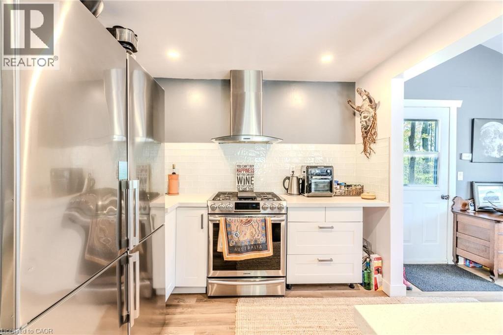 Contemporary kitchen featuring stainless steel appliances, a gas range with a hood vent, white cabinetry, and a subway tile backsplash