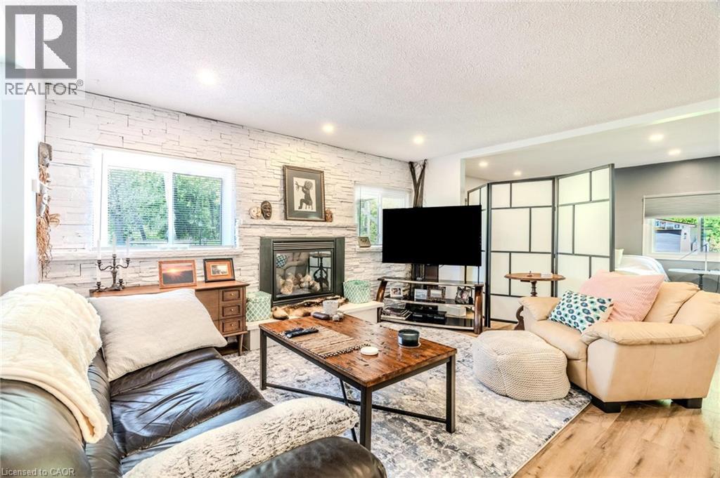 Living area featuring a textured accent wall with a fireplace, recessed lighting, and wood-finish flooring