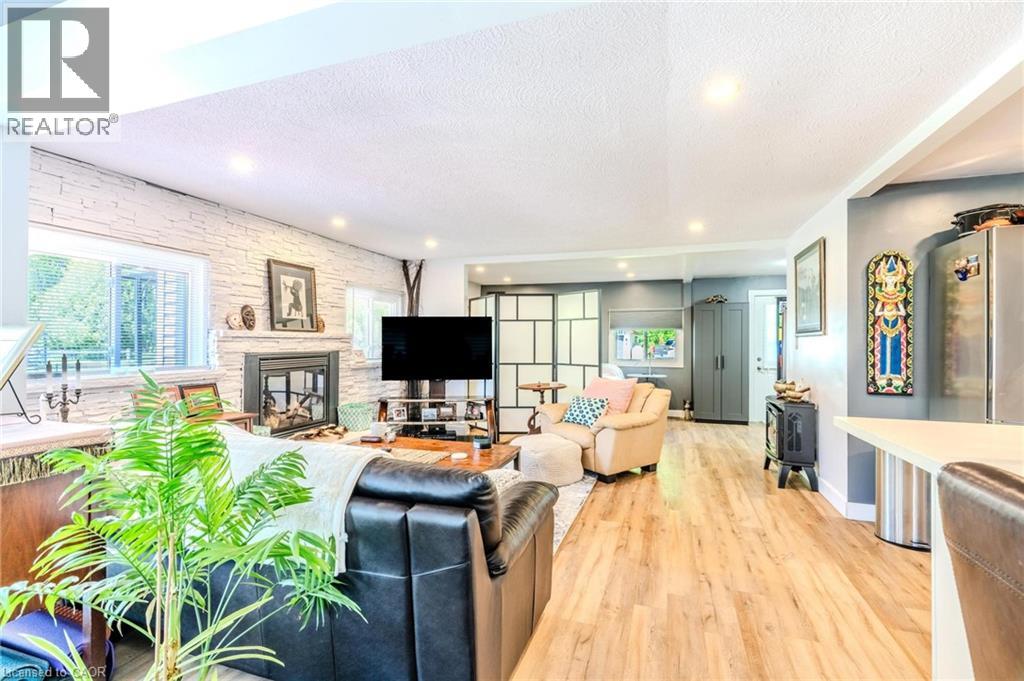 Open-concept living space featuring wood-finish flooring, recessed lighting, and a stone-clad fireplace