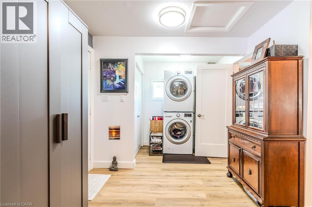 Dedicated laundry area featuring stacked appliances and wood-finish flooring