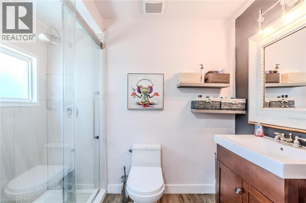 Bathroom featuring a glass-enclosed shower, a single vanity with a wood-finish cabinet, a rectangular sink, and a framed mirror
