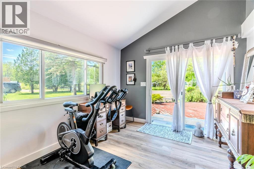 Room featuring large windows, wood-finish flooring, a vaulted ceiling, and sliding glass doors