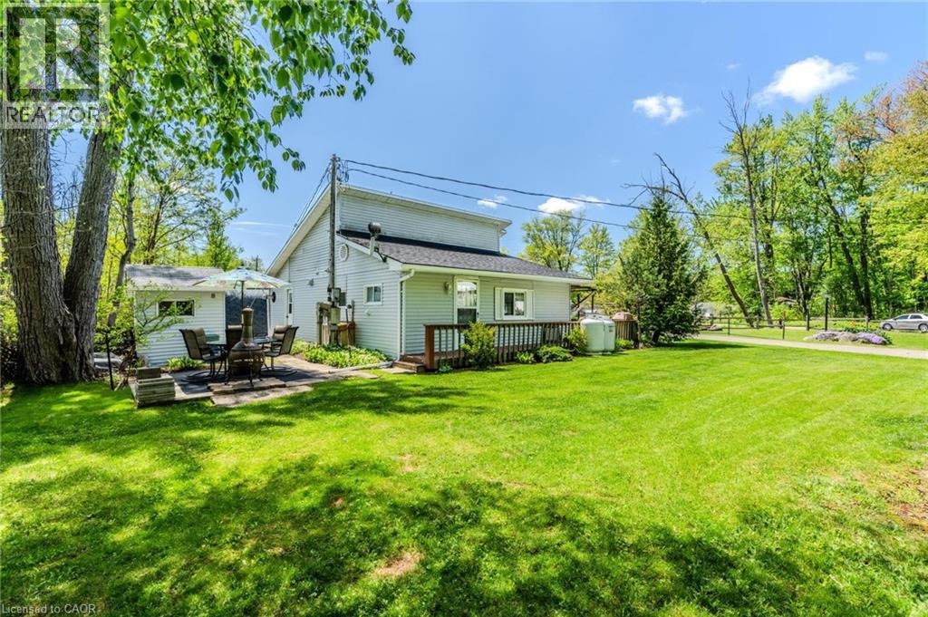 Spacious rear yard with a manicured lawn, featuring a stone patio and a detached shed