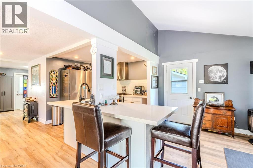 Kitchen area featuring a white countertop island with seating, stainless steel appliances, and wood-finish flooring