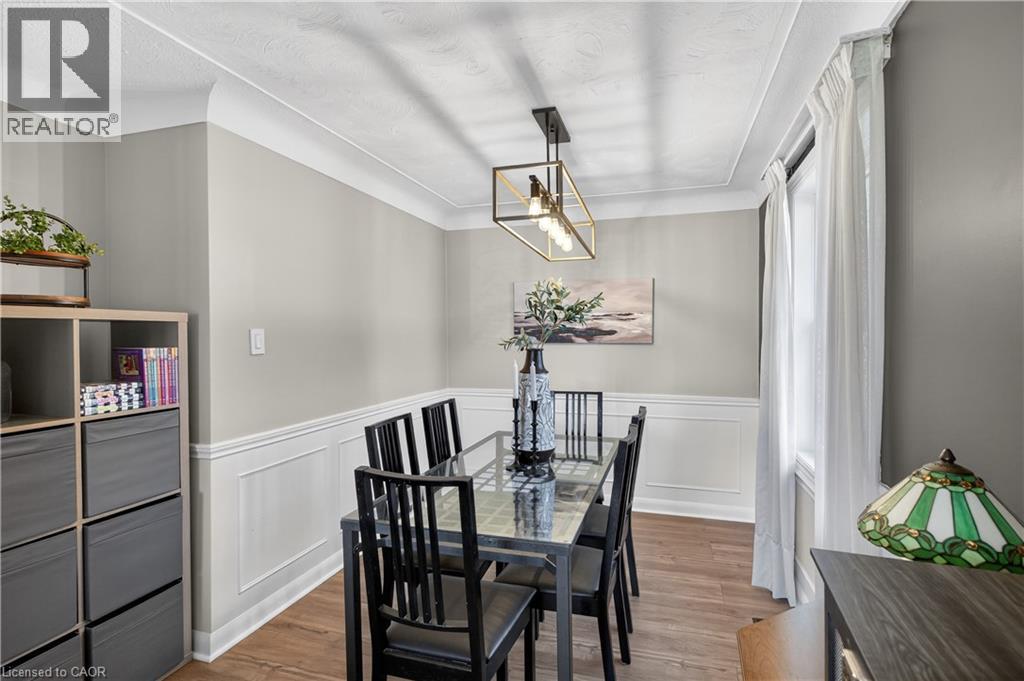 Dining area featuring a modern linear chandelier, crown molding, and wainscoting