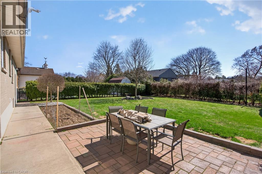 Brick paver patio with a concrete walkway, bordered by a raised garden bed and manicured lawn