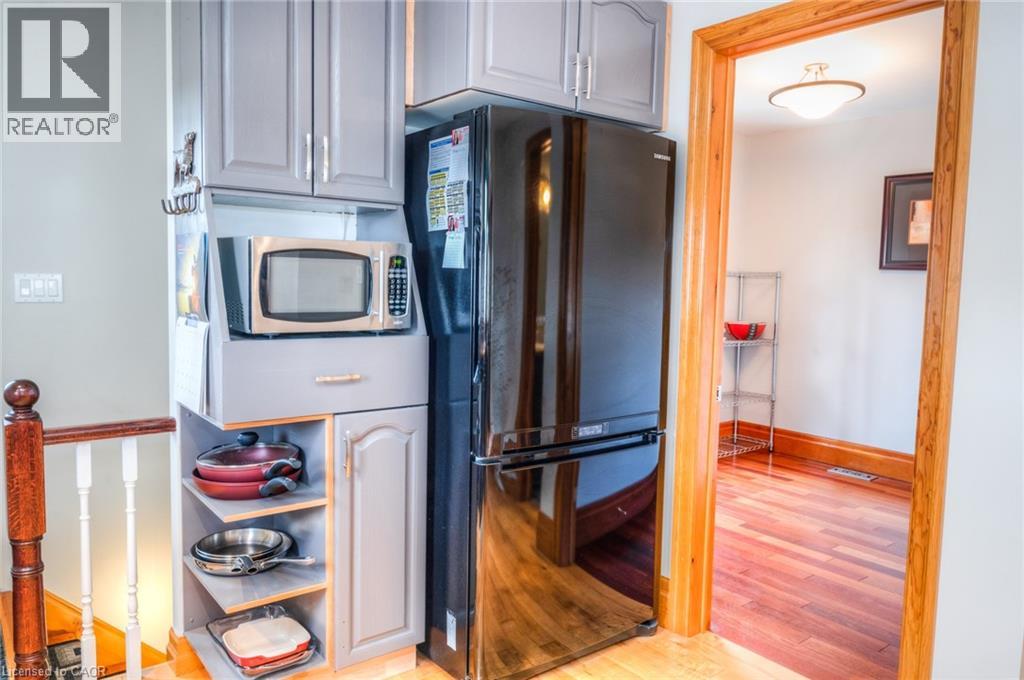 Integrated kitchen cabinetry featuring an overhead microwave niche, open shelving, a black refrigerator, and a lower storage cabinet
