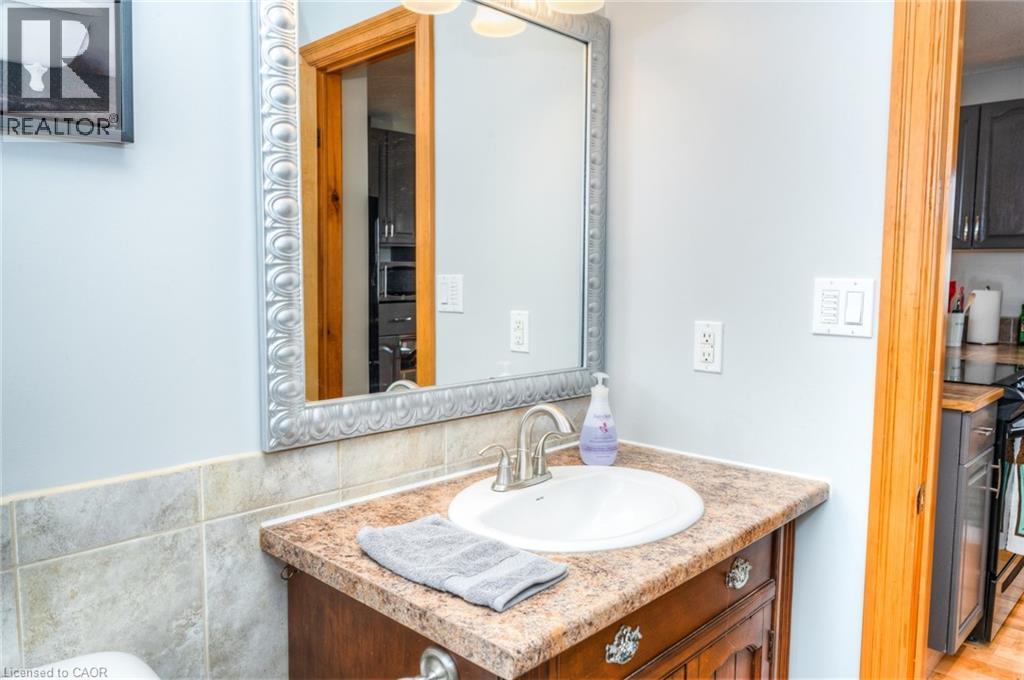 Powder room featuring a decorative framed mirror, single vanity with an integrated sink, and a tiled backsplash