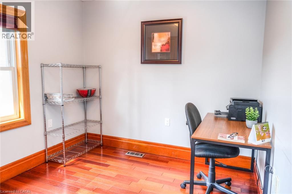 Room featuring wood-finish flooring, light grey walls, and natural wood trim around the window and baseboards