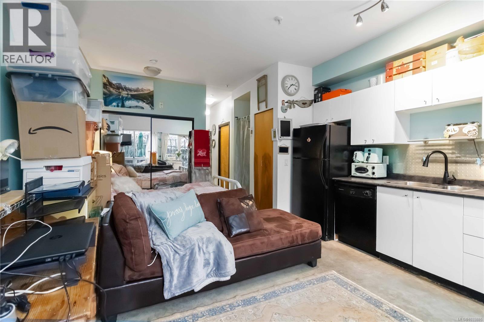 Kitchen featuring white cabinets, dark countertops, open floor plan, black appliances, and concrete floors