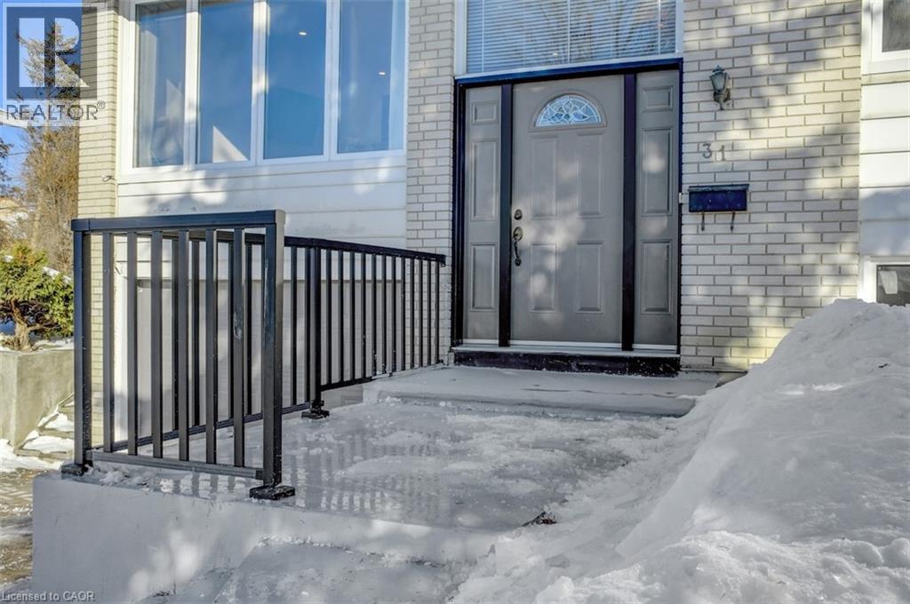 Entryway featuring a grey paneled door with an arched window, flanked by black trim and a black metal mailbox