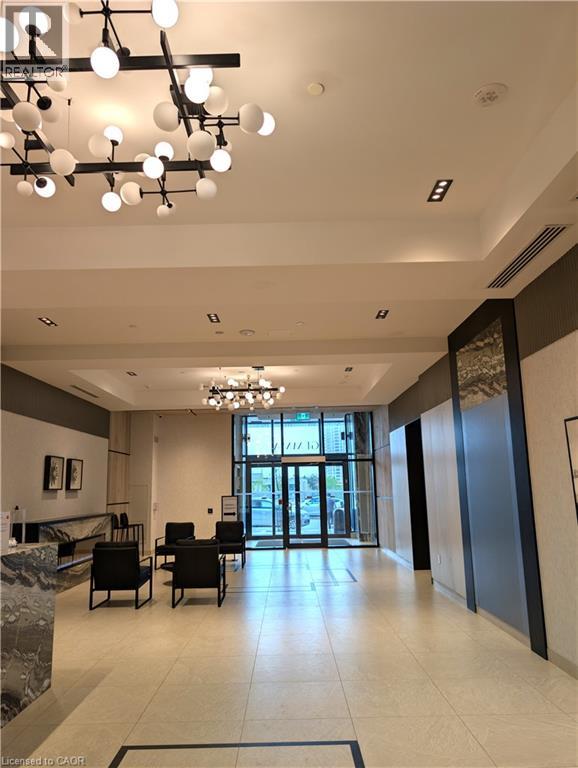 Spacious lobby featuring contemporary lighting, tiled flooring, a marbled reception counter, and a glass-paneled entrance