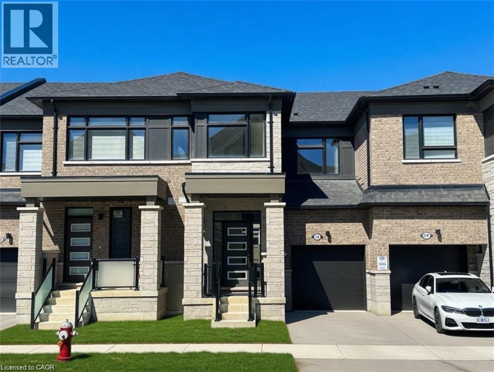 Modern townhome exterior featuring brick and stone cladding, dark shingles, black frame windows, and a covered front entry