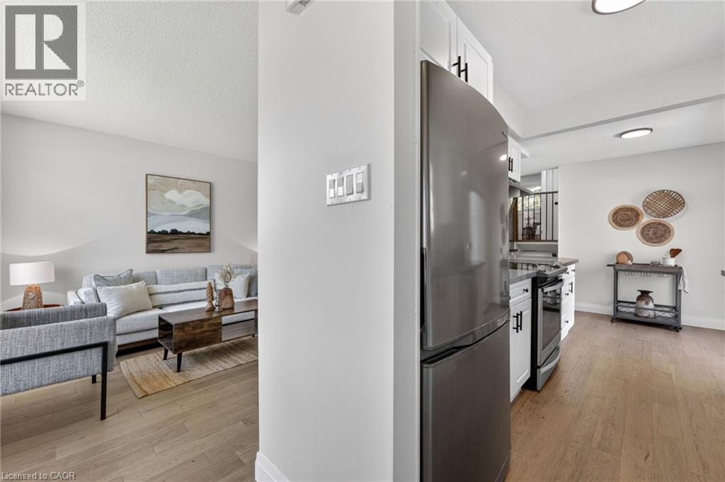 Kitchen featuring stainless steel appliances, white cabinetry with dark hardware, and wood-finish flooring