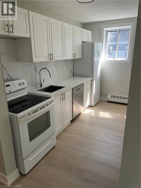 Modern kitchen featuring white shaker-style cabinetry, a white countertop, and a marble-look slab backsplash