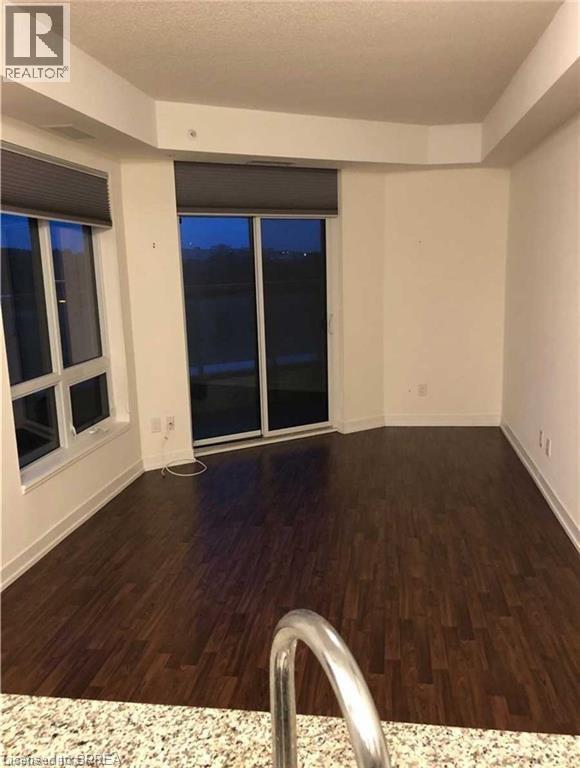 Spacious interior featuring dark wood-finish flooring, white baseboards, and a sliding glass door leading to an outdoor space