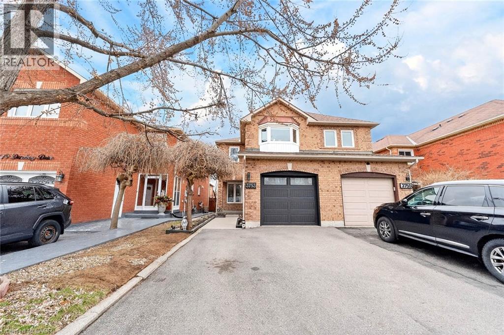 Brick exterior residence featuring two garage doors, one in black and one in beige