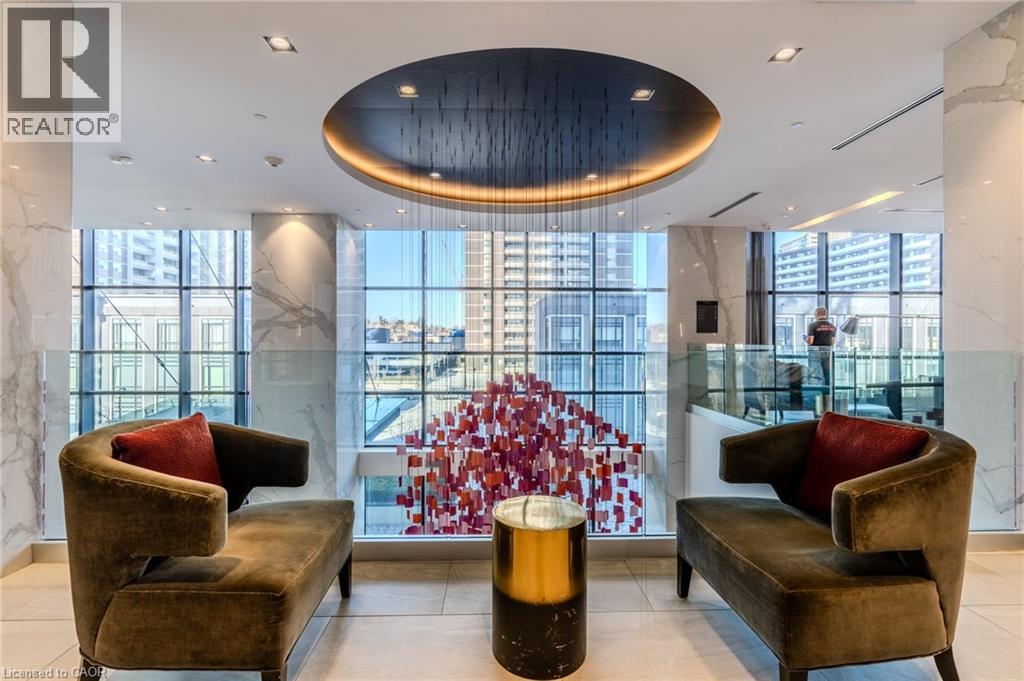 Lounge area featuring a circular recessed ceiling with accent lighting, full-height windows, a modern art installation, two contemporary chaises, and a metallic accent table
