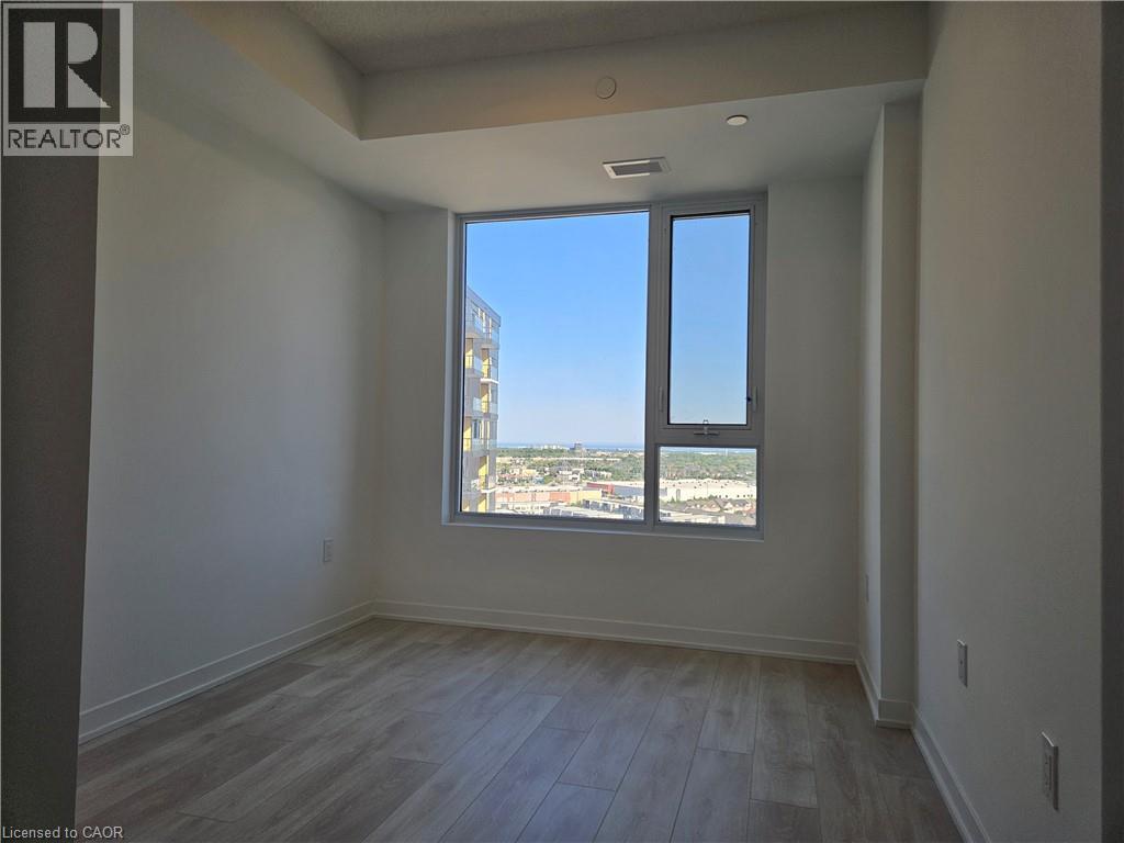 Spacious room featuring light wood-finish flooring, a contemporary window frame, and neutral wall tones