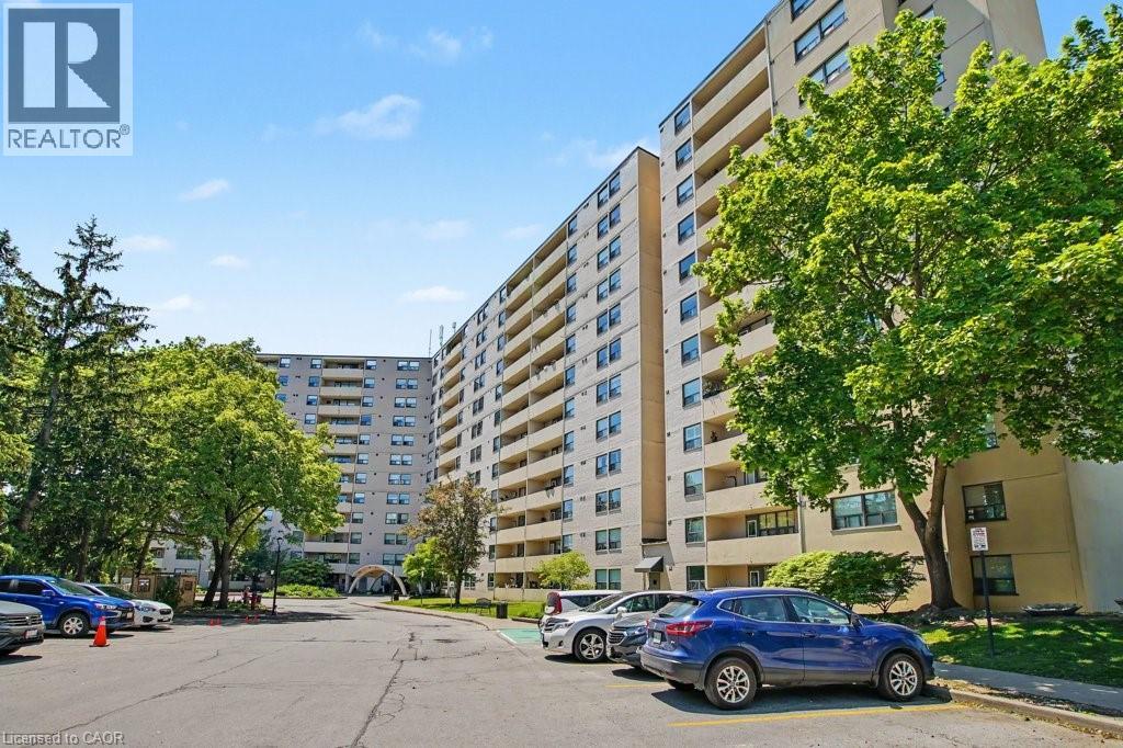 Multi-story residential building featuring numerous private balconies and a paved parking area