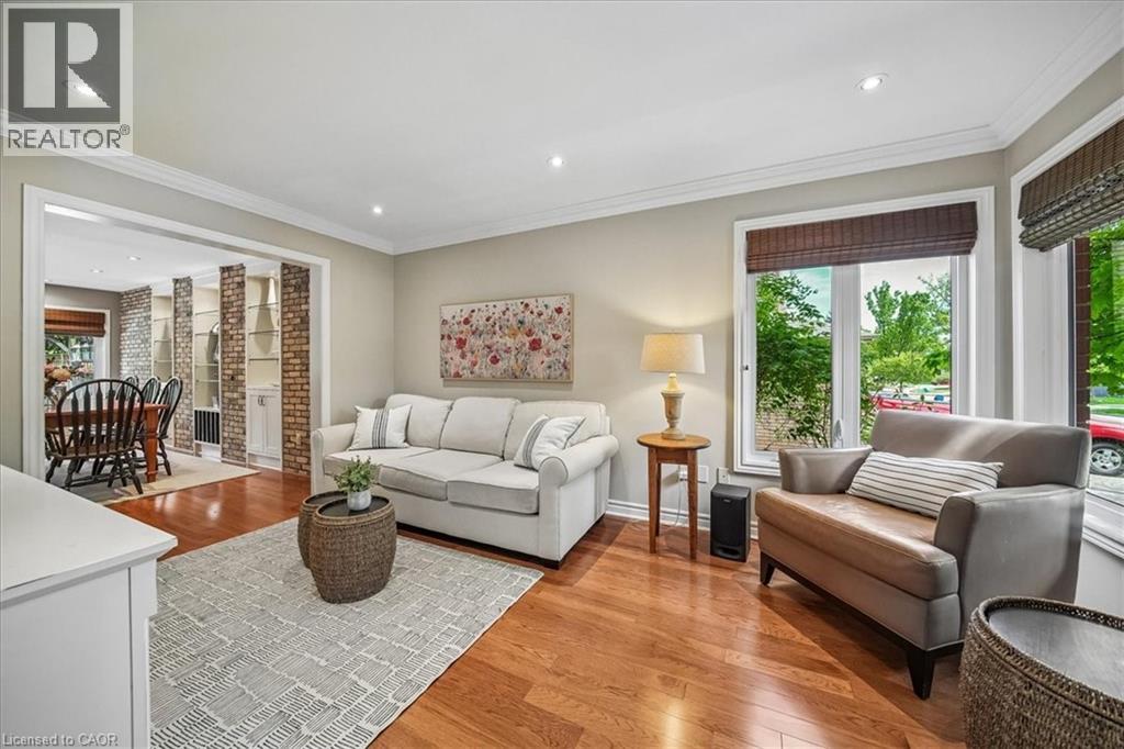 Hardwood-finish flooring extending through an open doorway, recessed lighting, crown molding, and large windows with natural light