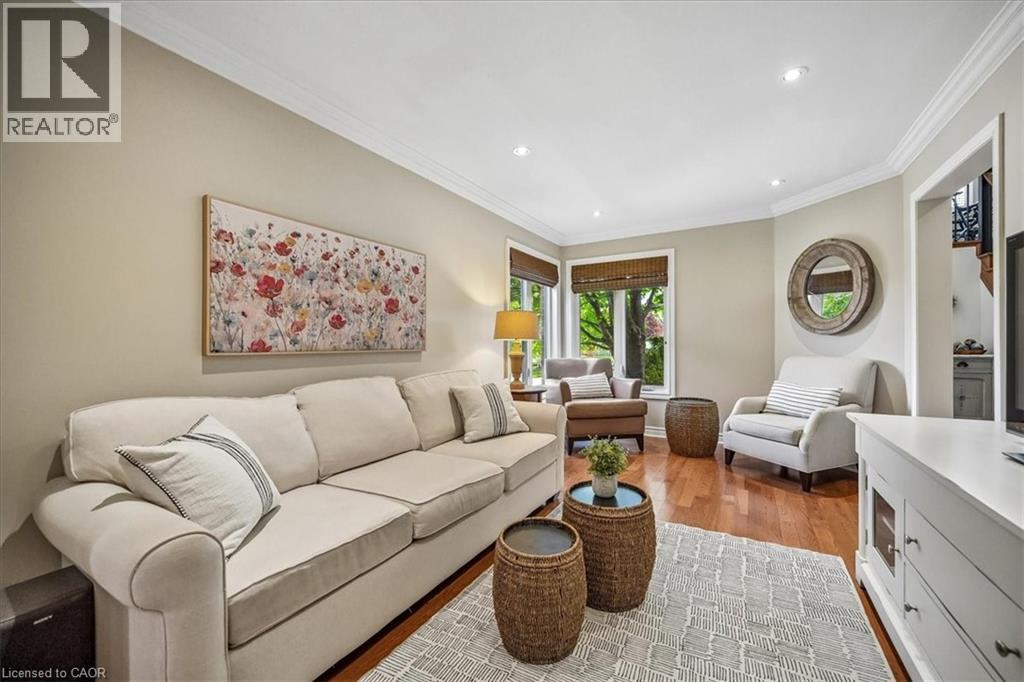 Living area featuring wood-finish flooring, recessed lighting, crown molding, and large windows with blinds