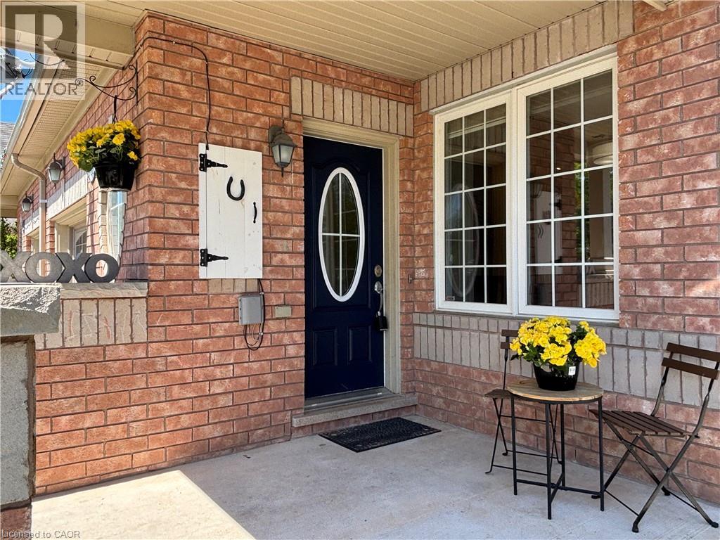 Front entrance featuring a dark-paneled door with an oval glass insert, a traditional lantern-style sconce, and red brick siding with light-colored brick accents